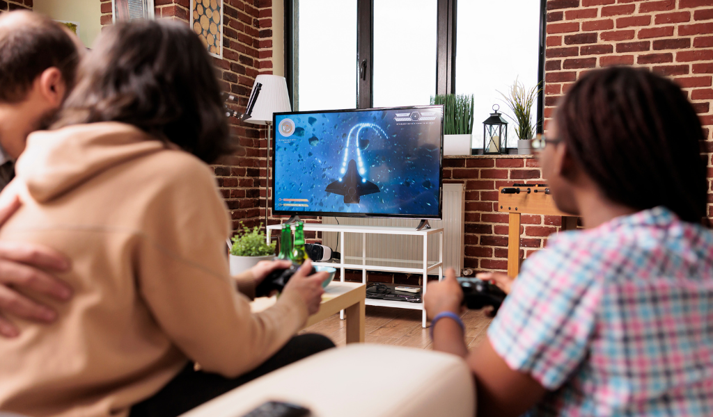 Trois individus jouent ensemble à un jeu vidéo sur une télé